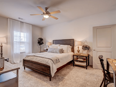 A bedroom with a bed, nightstand, and chair.