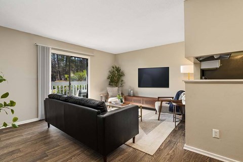 A living room with a black couch and a flat screen TV mounted on the wall.