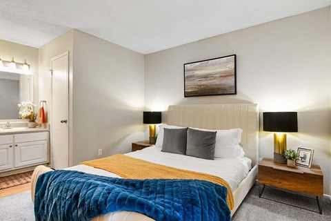 A bedroom with a bed, nightstand, and a painting on the wall.