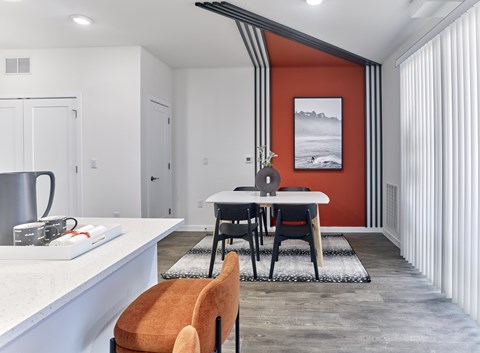 A kitchen with a white countertop and a dining table with chairs.