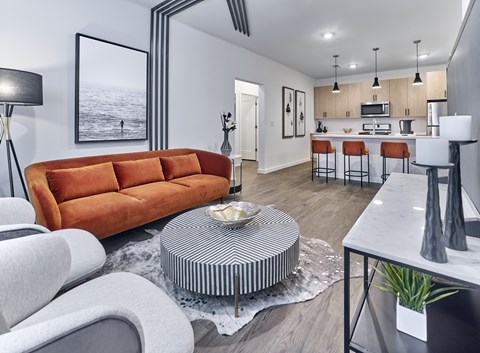 A modern living room with a large orange sofa and a striped coffee table.