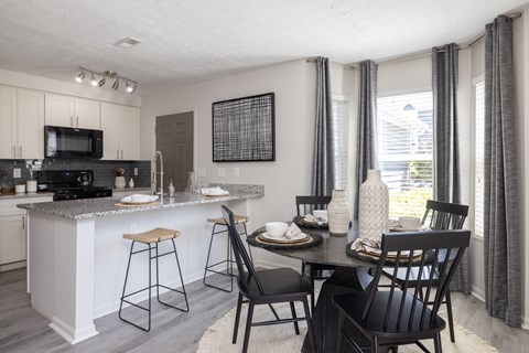 A kitchen with a bar and chairs.