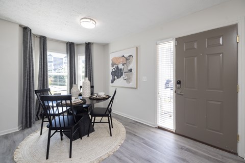 A dining room with a table set for two and a painting on the wall.