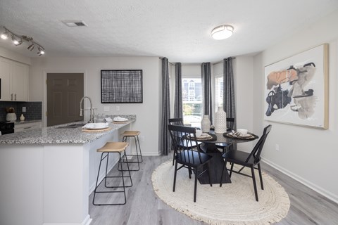 A kitchen with a bar and a dining table with chairs.