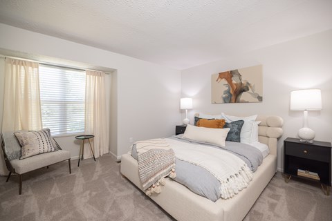 A bedroom with a large bed and a chair.