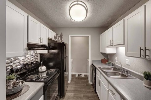 A kitchen with black appliances and white cabinets.