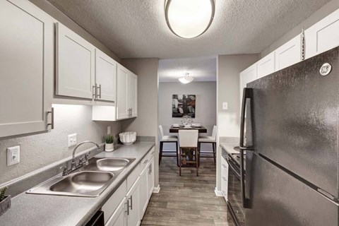 A kitchen with a refrigerator, sink, and dining table.