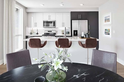 A modern kitchen with a black marble table and chairs.