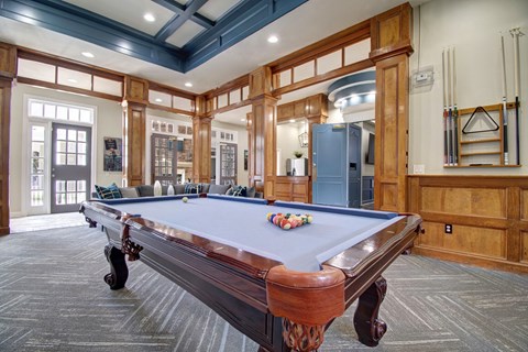 A pool table in a room with wooden walls and a blue ceiling.