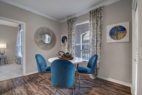 A dining room with a round table and blue chairs.