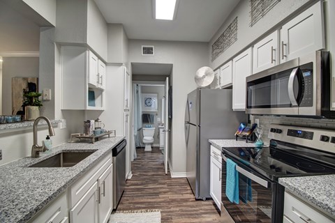 A modern kitchen with granite countertops and stainless steel appliances.