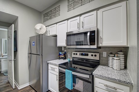 A kitchen with a stainless steel refrigerator, microwave, and oven.