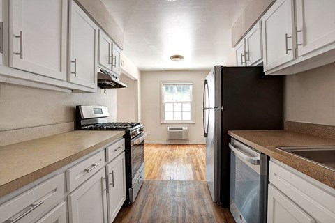 A kitchen with white cabinets and a black refrigerator.