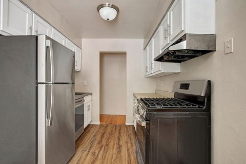 A kitchen with a stainless steel refrigerator and a black stove top oven.