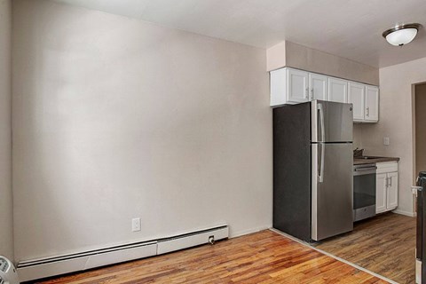A kitchen with a black fridge and wooden floors.