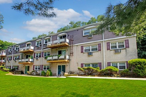 Apartment building with balconies and green lawn in front.