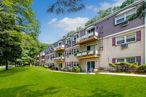 A row of apartment buildings with green lawns in front.