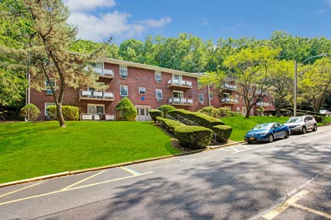 A red brick apartment building with a green lawn in front.