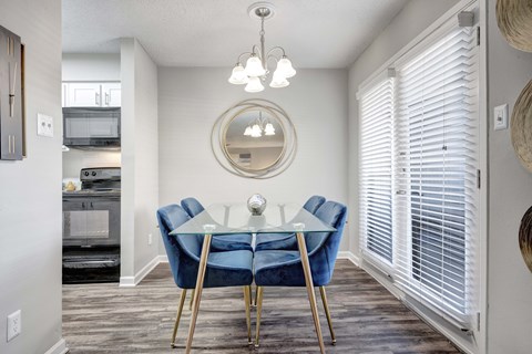 A dining room with a glass table and blue chairs.