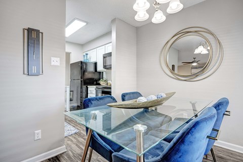 A modern dining room with a glass table and blue chairs.