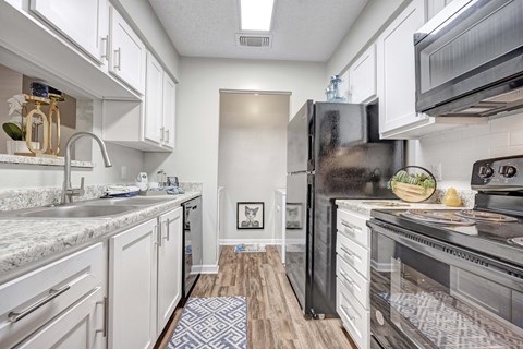 A kitchen with a black refrigerator and white cabinets.
