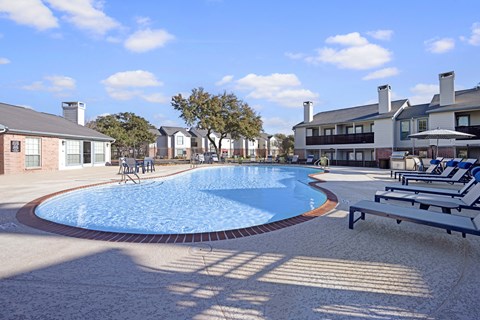 A swimming pool surrounded by a concrete floor and a bench.