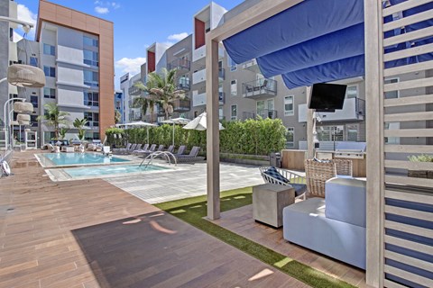 A pool area with a wooden deck and lounge chairs.