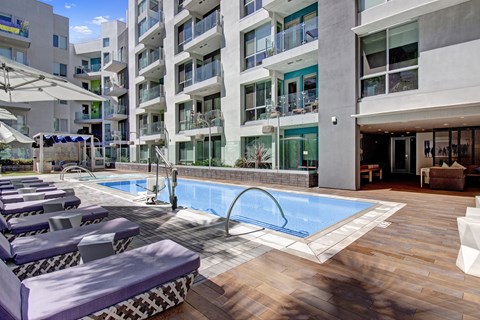 A pool area with lounge chairs and a building in the background.