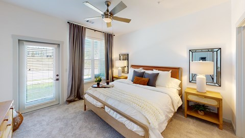 A bedroom with a large bed, a ceiling fan, and a window with blinds.