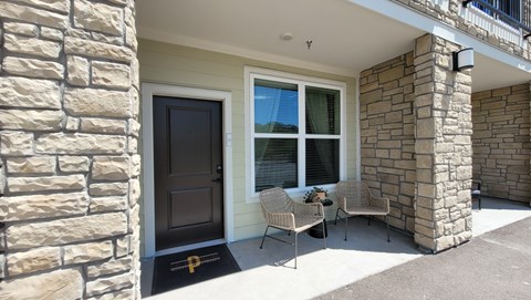 A house with a black door and a window with white curtains.