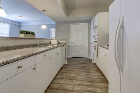 A kitchen with white cabinets and a white refrigerator.