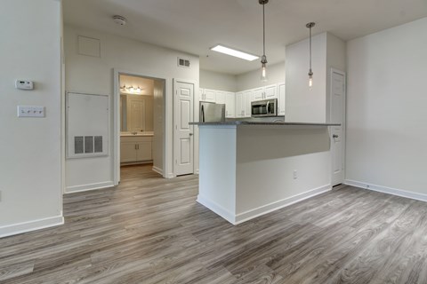 A kitchen with a white counter and cabinets with a wood floor.