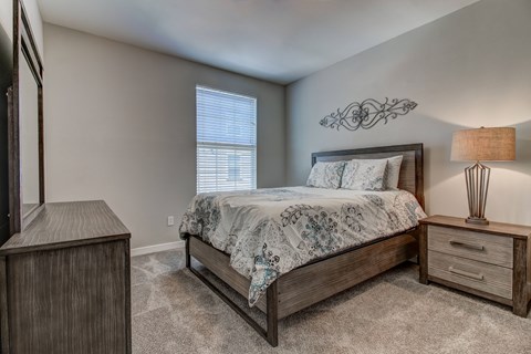 A bedroom with a large bed and a wooden nightstand.
