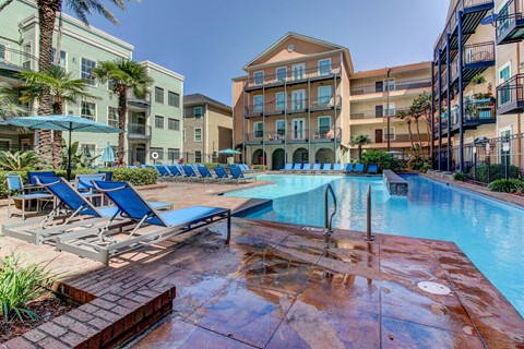 A pool surrounded by lounge chairs and umbrellas.