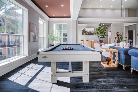A pool table is in the middle of a room with a blue couch and a white chair.