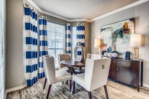 A dining room with a table set for two and a painting on the wall.