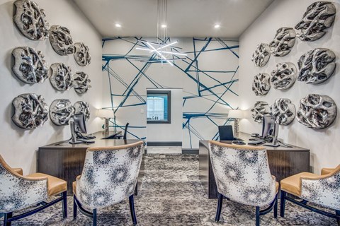 A room with a desk and chairs in front of a wall with skulls on it.