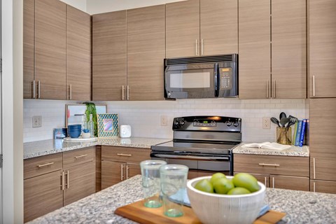 A kitchen with a bowl of green apples on a cutting board.