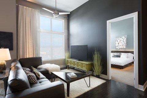 A living room with a black couch and a television.
