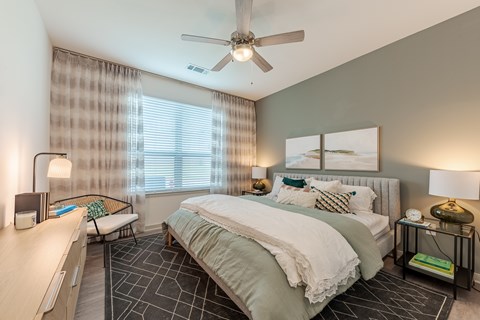 A bedroom with a bed, nightstands, and a ceiling fan.