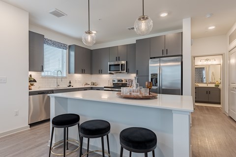 A modern kitchen with a bar area and two black stools.