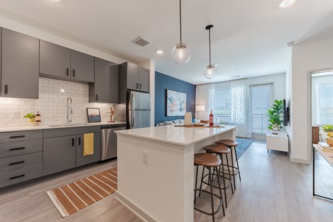 A modern kitchen with a white island and bar stools.