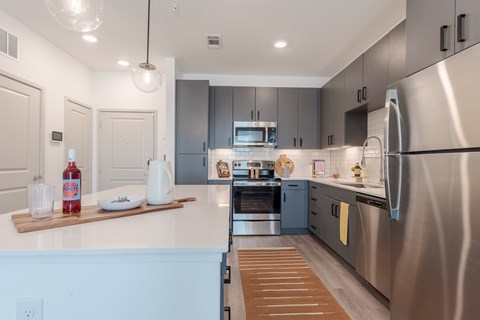 A modern kitchen with a white countertop and stainless steel appliances.