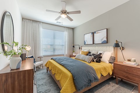 A bedroom with a bed, nightstand, and a ceiling fan.