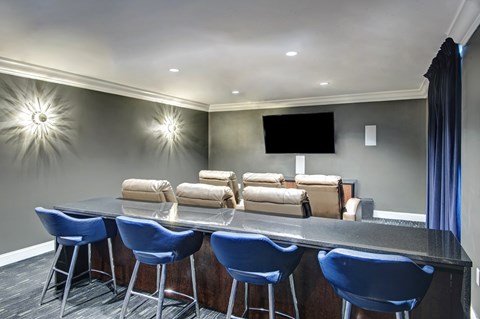 A modern dining area with a bar and blue chairs.