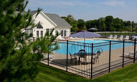 A pool surrounded by a black fence with a house in the background.