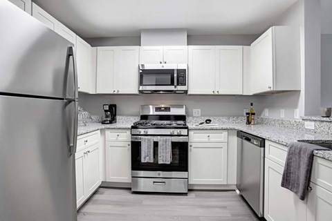 A modern kitchen with white cabinets and stainless steel appliances.