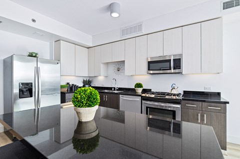 A modern kitchen with a refrigerator, microwave, and stove top oven.