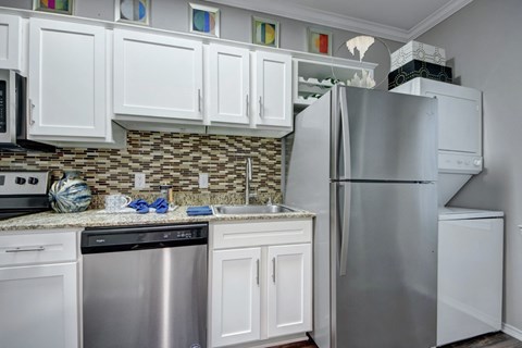 A kitchen with white cabinets and a stainless steel refrigerator.