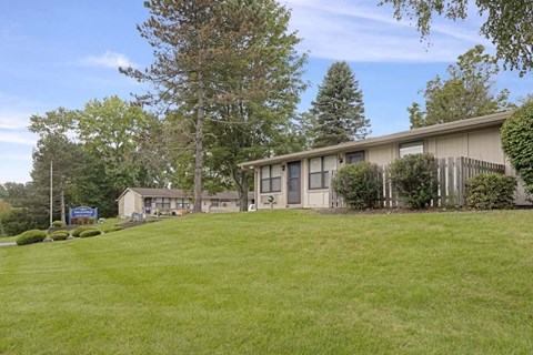 A large grassy area in front of a building with trees.